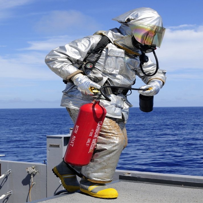 Posterazzi Firefighter carries a CO2 fire extinguisher onto the flight deck of USS Denver Poster Print, (24 x 33)